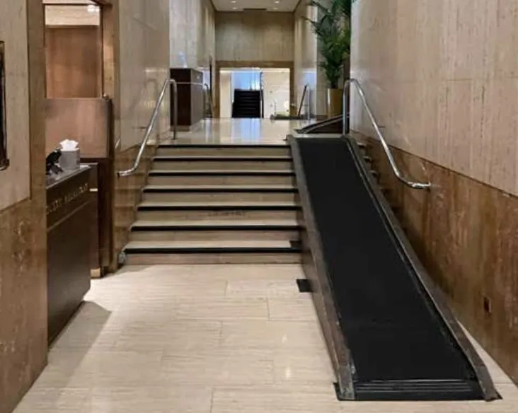 Entrance hall where a long temporary ramp runs up the middle of a flight of steps.