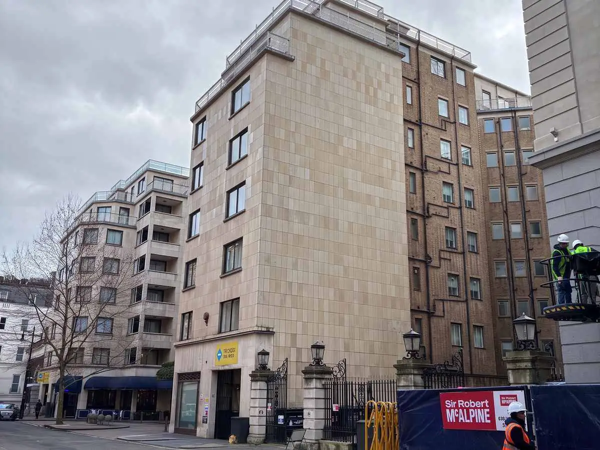 Arlington House as existing: a stone-faced block on Arlington Street beside neighbouring buildings, with hoarding at street level.